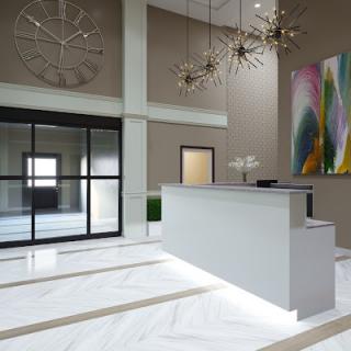 A modern and minimalist reception area featuring a sleek desk, abstract artwork, and elegant chandeliers.