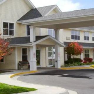 A residential building with a covered entrance and landscaped surroundings.