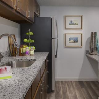 A modern kitchen with granite countertops, wooden cabinets, and stainless steel appliances.