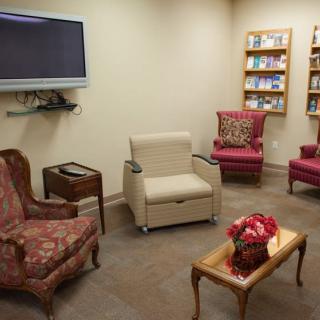 A cozy waiting room with comfortable chairs, a television, and bookshelves.