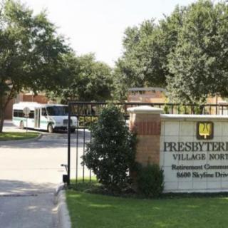 Entrance to a facility with a sign and surrounding trees.