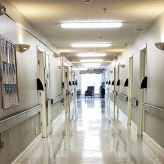 A clean and well-lit hospital hallway with doors leading to rooms on either side.