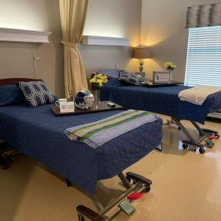 A hospital room with two beds, each equipped with trays and decorative flowers.