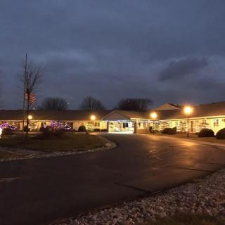 A well-lit building at dusk with a parking lot and cloudy sky.