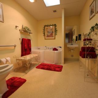 A well-decorated bathroom with red accents, featuring a bathtub, sink, and neatly arranged towels.