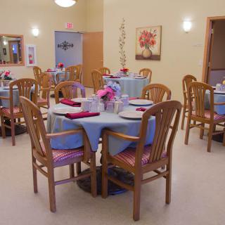 A well-decorated dining room with neatly arranged tables and chairs, featuring elegant table settings.