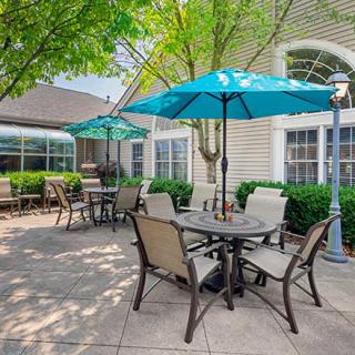 A sunny patio area with tables, chairs, and umbrellas.