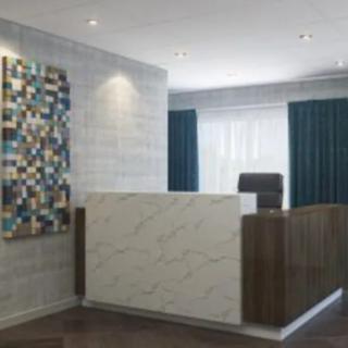 A modern office reception area featuring a large desk and colorful artwork on the wall.