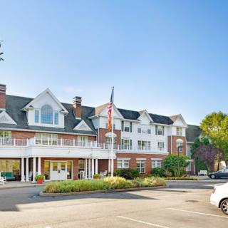 A large residential building with a driveway and well-maintained landscaping on a sunny day.