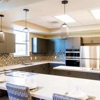 A modern kitchen with sleek cabinetry, a central island, pendant lighting, and stainless steel appliances.