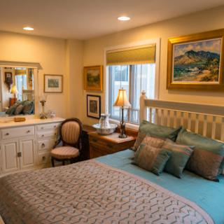A cozy and inviting bedroom featuring tasteful decor, comfortable bedding, and artwork that adds a personal touch.