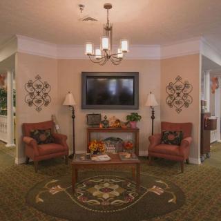 A cozy living room with traditional decor, featuring a chandelier, two armchairs, and wall art.