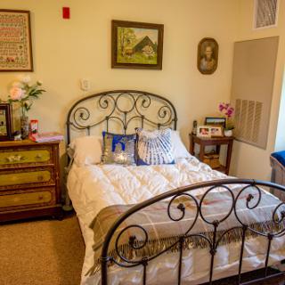 A cozy bedroom featuring a wrought iron bed frame, decorative pillows, and charming wall art.