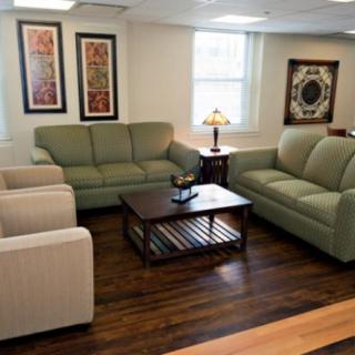 A cozy living room with sofas and armchairs arranged around a wooden coffee table.