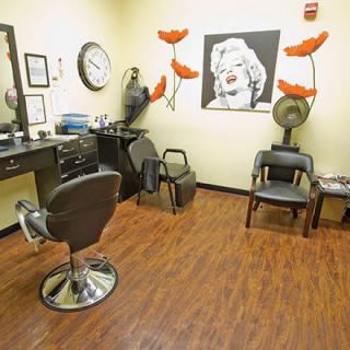 Interior of a hair salon with chairs, a mirror, and wall art.