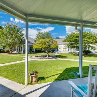 A peaceful view from a covered patio overlooking a well-maintained garden and lawn on a sunny day.