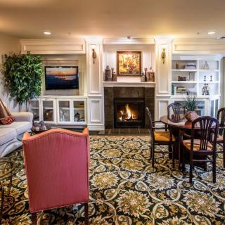 A cozy living room with a fireplace, elegant furniture, and intricate carpet design.