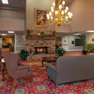 A cozy lobby with a warm fireplace, elegant chandelier, and comfortable seating area.