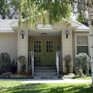 Front view of a house with a porch and green door, surrounded by trees and landscaping.