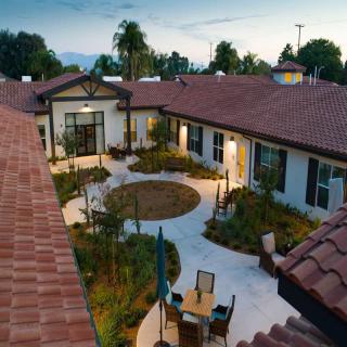 A serene courtyard with outdoor seating surrounded by lush greenery during the evening.