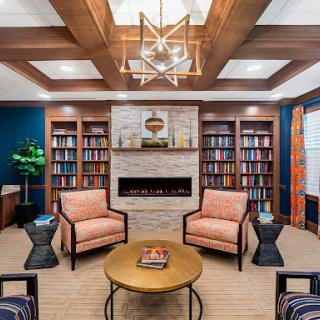 A stylish and cozy modern library with comfortable seating, a fireplace, and well-organized bookshelves.