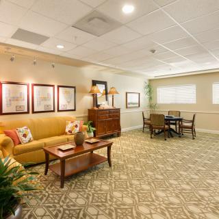 A cozy living room space featuring a comfortable sofa, artwork on the walls, and a small dining area.