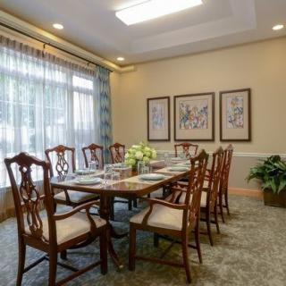 A well-decorated dining room with a large table and chairs, artwork on the walls, and a window allowing natural light.
