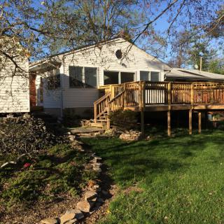 A cozy house with a wooden deck and a well-maintained yard basking in sunlight.