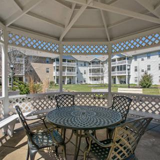 A peaceful gazebo with a table and chairs, perfect for relaxation in a residential setting.