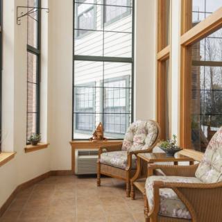 A cozy sunroom with large windows, featuring comfortable wicker chairs and natural lighting.