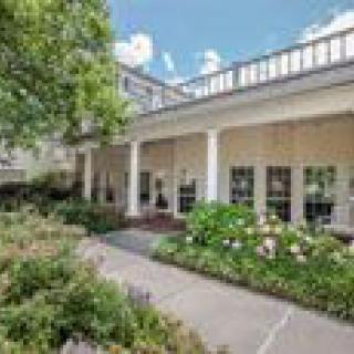 A scenic view of a building with a garden and pathway surrounded by lush greenery.