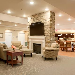 A modern living room with a cozy seating area, featuring a stone fireplace and a mounted television.