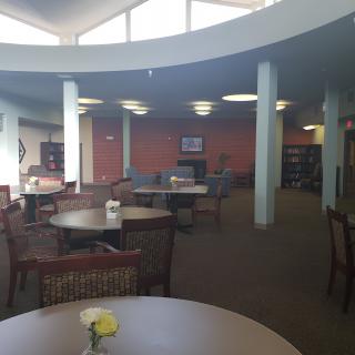 A quiet library study area with tables, chairs, and bookshelves.