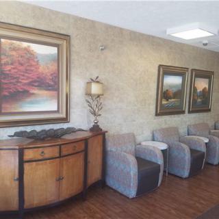 A well-furnished waiting room featuring comfortable chairs and scenic paintings on the wall.