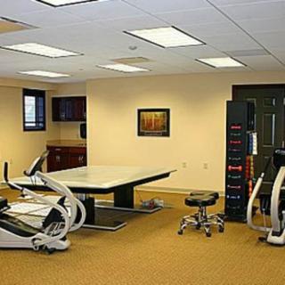 A well-equipped gym with exercise machines and a table in a healthcare facility.