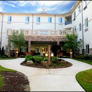 A well-maintained building entrance with landscaped greenery and a clear pathway.