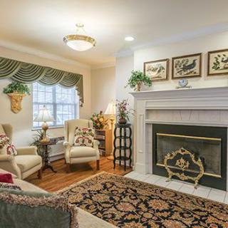 A cozy living room with traditional decor, featuring a fireplace and comfortable armchairs.