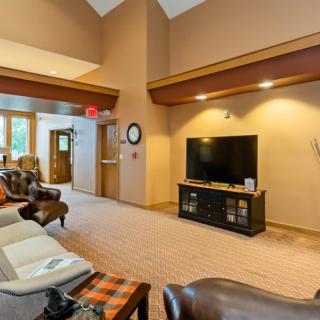 A spacious living room featuring comfortable seating, a large TV, and warm interior accents.