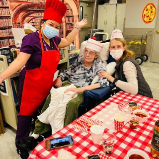 A joyful cooking activity with staff and a resident, celebrating together in a warm community setting.
