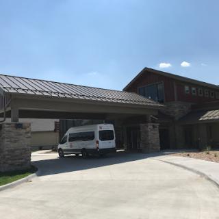 A modern building entrance with a vehicle parked under the awning.