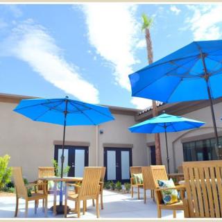 A sunny outdoor patio area with modern furniture and blue umbrellas.