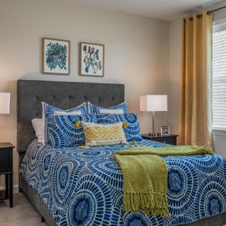 A stylish bedroom with vibrant blue patterned bedding, complemented by yellow accents and elegant decor.