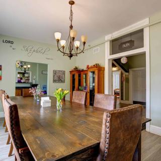 A cozy dining room featuring a large wooden table, leather chairs, and a decorative chandelier.