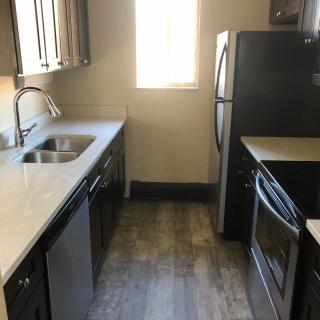 A modern kitchen with a stove, refrigerator, and sink.