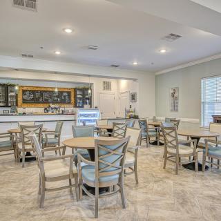 An empty cafe interior with tables and chairs arranged neatly, featuring a bar area.