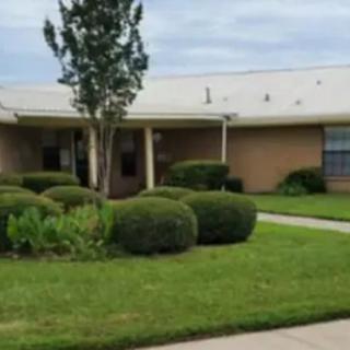 A suburban house with a well-maintained lawn and neatly trimmed bushes.