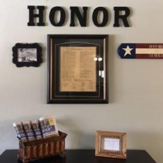 A wall display featuring the word 'HONOR', a framed document, and a Texas-themed decoration.