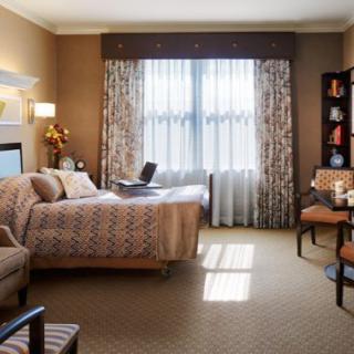 A cozy and well-decorated bedroom with a comfortable bed, chairs, and a window providing natural light.