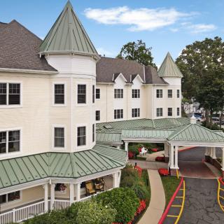 A multi-story residential building with pointed roofs and a landscaped entrance.