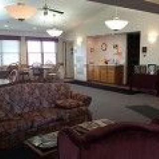 A cozy living room with sofas, warm lighting, and carpeted flooring.